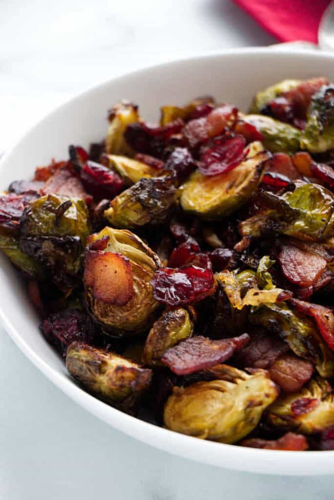 a serving bowl with air fryer Brussels sprouts with bacon onions and cranberries