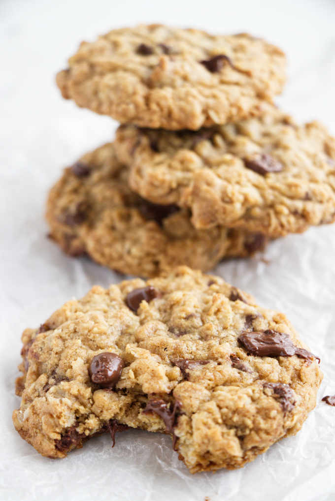 Cookies on parchment paper, one with a bite taken out of it.