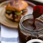 pumpkin spice bbq sauce dripping from utensil and pulled pork sandwich in background