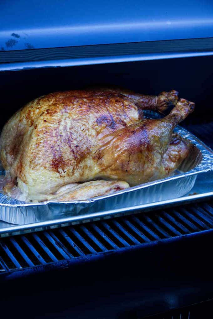 A turkey in a roasting pan on a pellet grill.