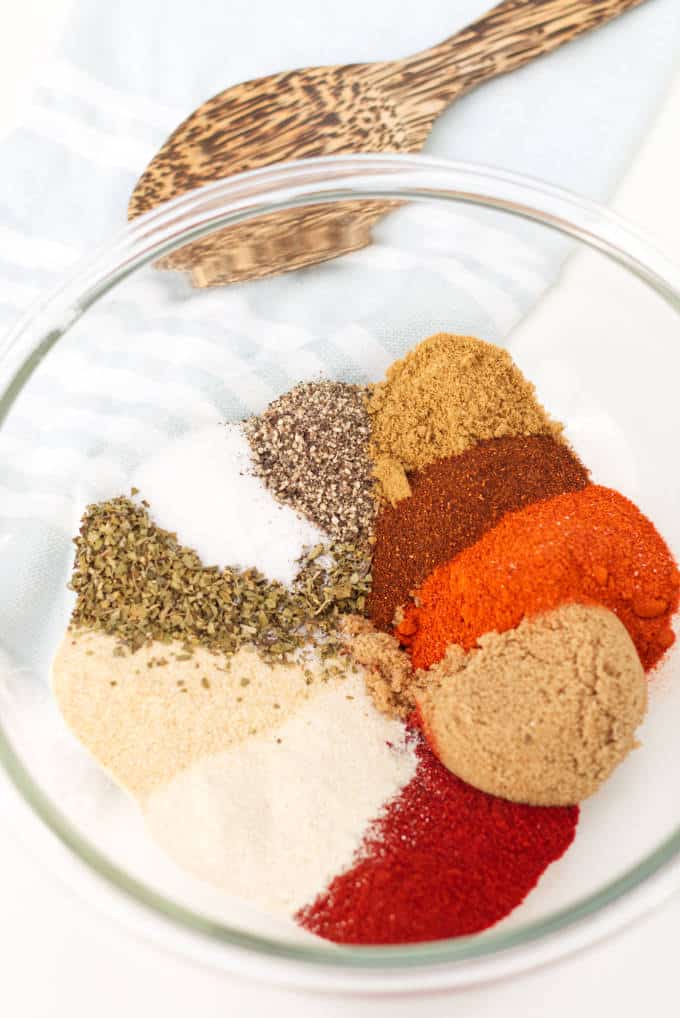 spices for barbecue spice blend arranged in a glass bowl sitting on a white table with blue and white towel