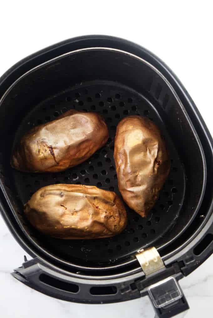 Three sweet potatoes in an air fryer.