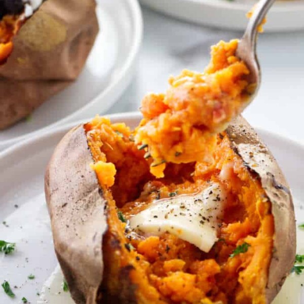 A fork digging into an air fryer baked sweet potato.