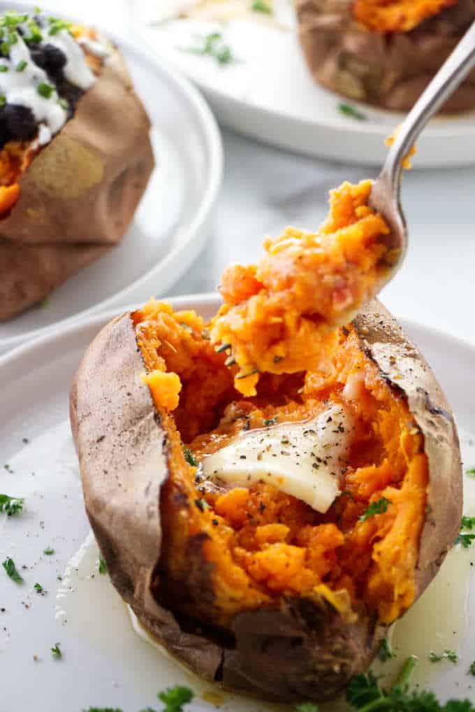 A fork digging into an air fryer baked sweet potato.