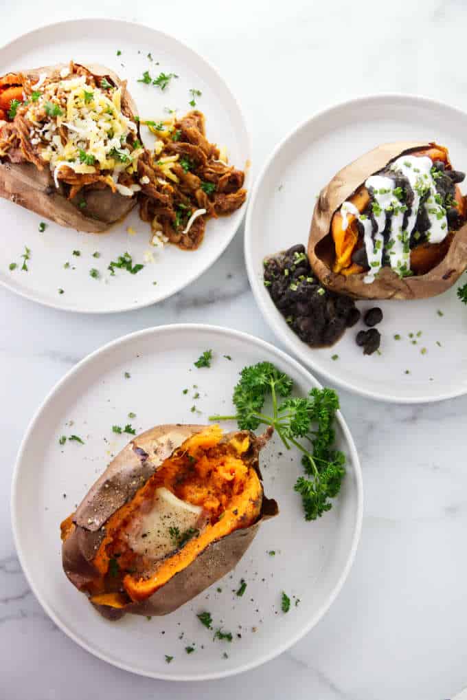 Three air fryer baked sweet potatoes with pulled pork, black beans, and butter.