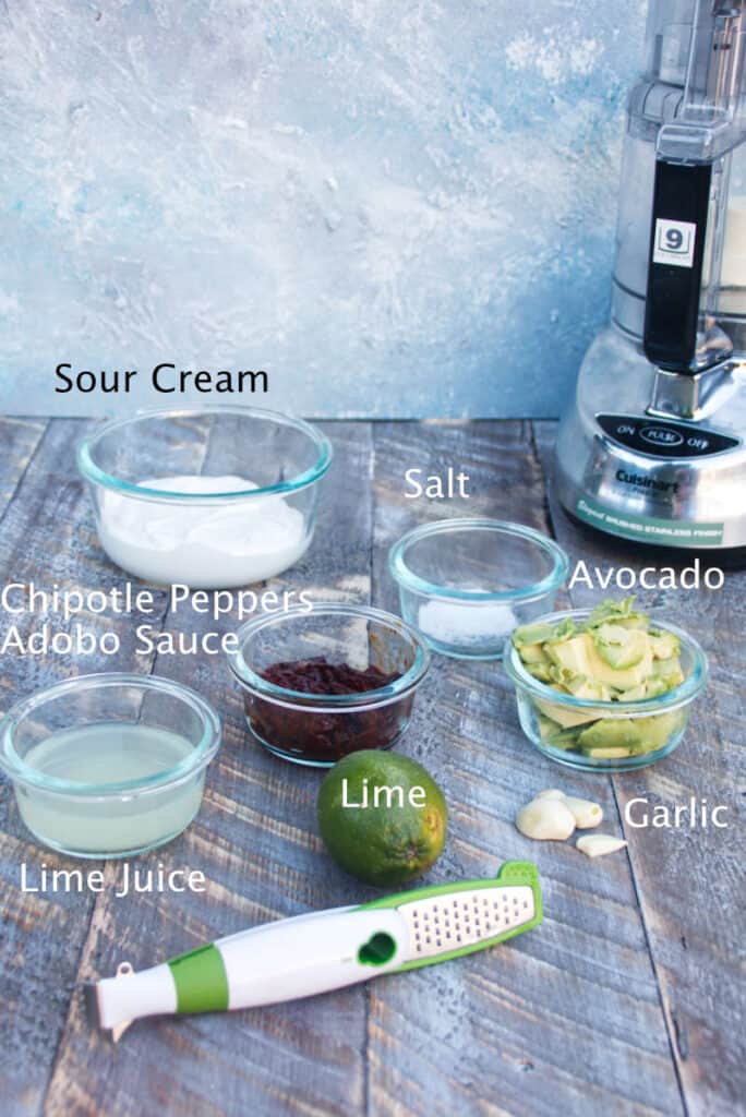 ingredients for chipotle lime crema sour cream, salt, avocado, chipotle peppers, adobo sauce, whole lime for zest, garlic cloves, with food processor and microplane