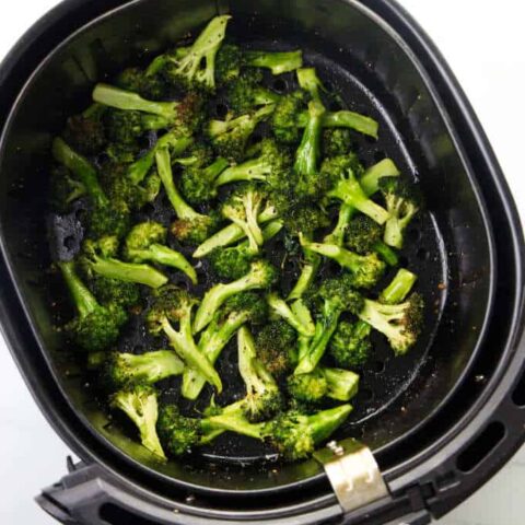 Broccoli in an air fryer basket.