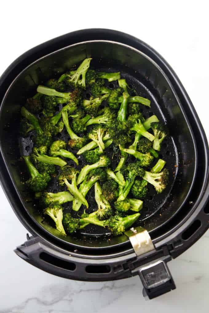 Broccoli in an air fryer basket.