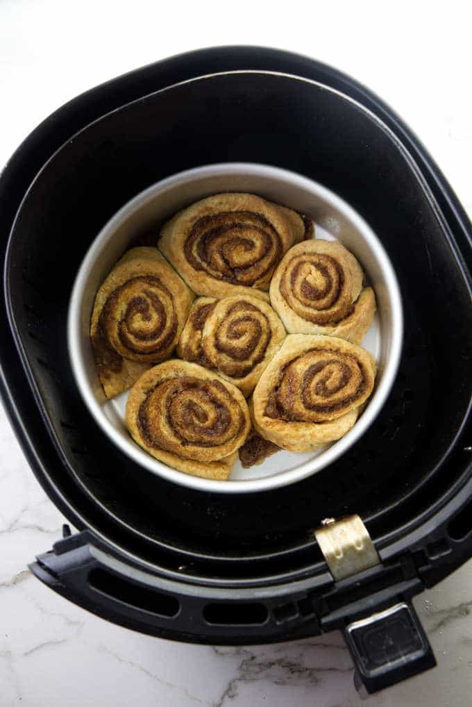 Hot cinnamon rolls in an air fryer basket.