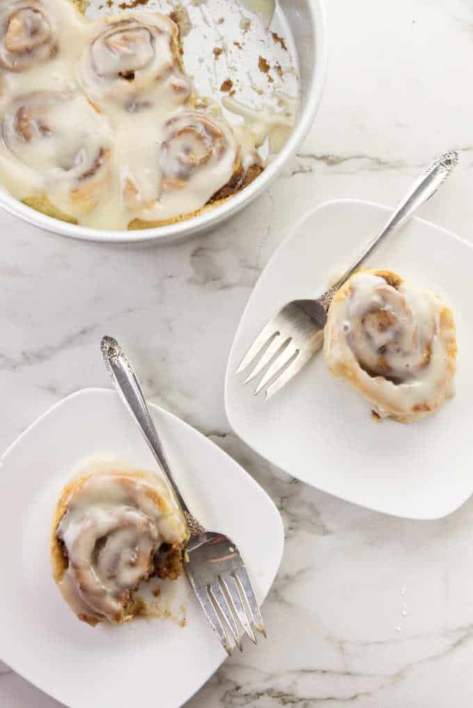 Two cinnamon rolls on plates.