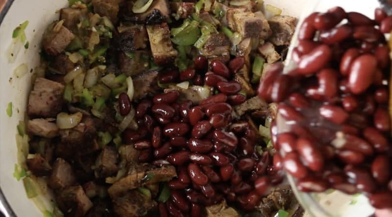 red kidney beans being poured into base of smoked brisket chili