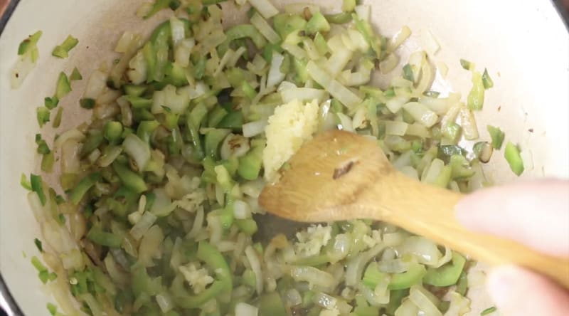 photo of veggies cooking in dutch oven, onion, green bell peppers, jalapeño, and garlic