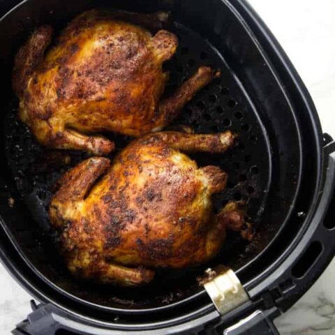 Two Cornish game hens in an Air Fryer basket.