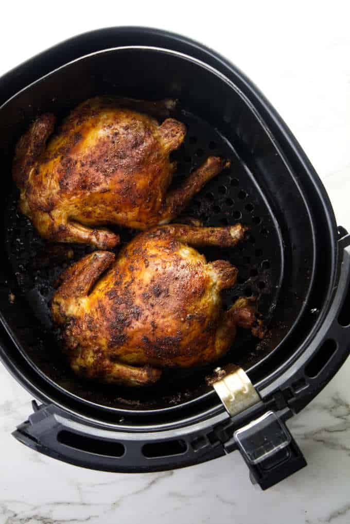 Two Cornish game hens in an Air Fryer basket.