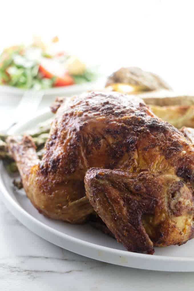 Cornish game hen with a salad in the background.