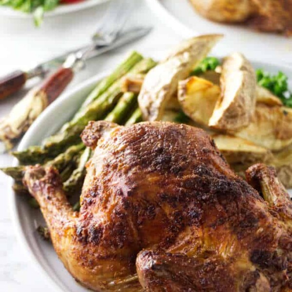 Cornish game hens on a plate with asparagus and potatoes.