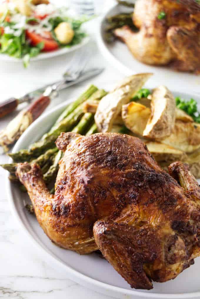 Cornish game hens on a plate with asparagus and potatoes.