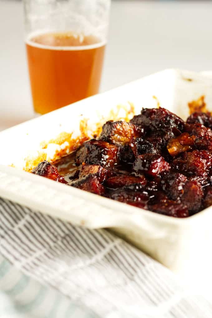Smoked brisket burnt ends in a white dish covered in BBQ sauce.