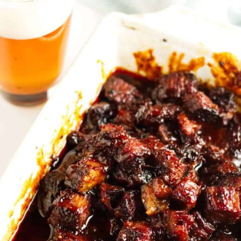 Smoked brisket burnt ends in a white dish covered in BBQ sauce.