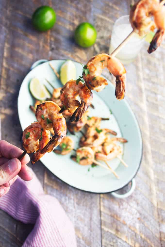 skewer with 5 grilled tequila lime shrimp held by hand