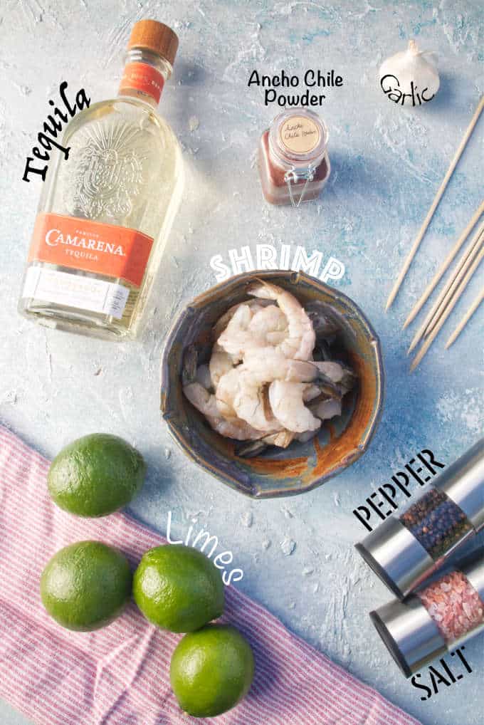 ingredients for tequila lime shrimp, garlic, ancho chile powder, pepper, salt, skewers, with red and white napkin