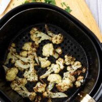 Roasted cauliflower in an air fryer basket.