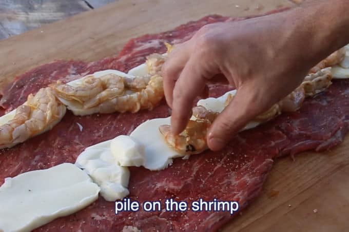 placing shrimp and cheese on butterfly flank steak