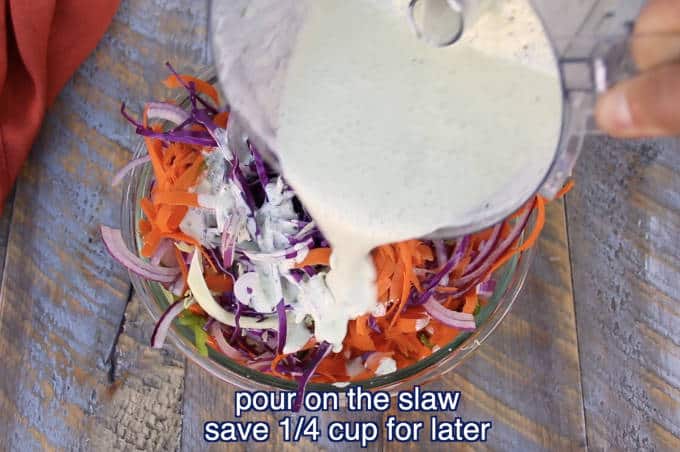 chopped vegetable ingredients for jalapeño lime cilantro slaw in a glass bowl with dressing being poured on on wood table