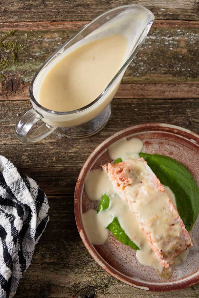 orange lemon butter sauce drizzled on top of a grilled salmon fillet with gravy boat of sauce