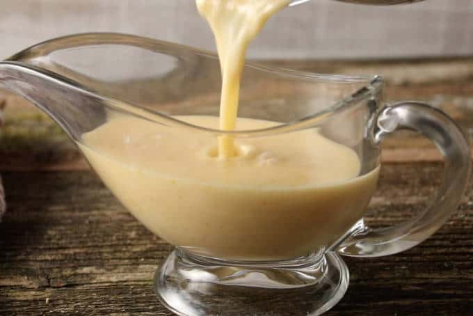 pouring orange lemon butter sauce beurre blanc into gravy boat