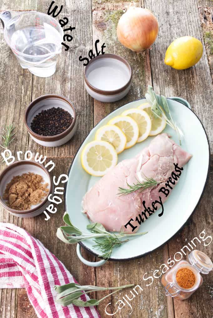 Ingredients picture of smoked wild turkey breast: water, salt, brown sugar, cajun seasoning and turkey breast. Other aromatics pictured like onion, black peppercorn, lemon, sage, rosemary.