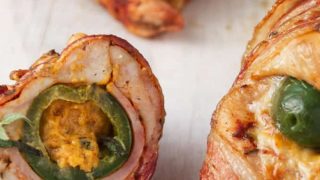 Bacon-wrapped chicken breast stuffed with a jalapeno popper, slices of ham, and cheese