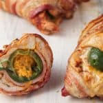 Bacon-wrapped chicken breast stuffed with a jalapeno popper, slices of ham, and cheese