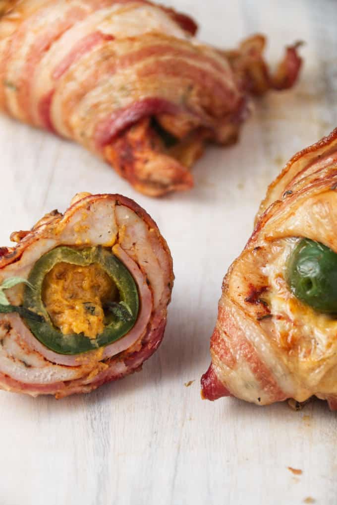 Bacon-wrapped chicken breast stuffed with a jalapeno popper, slices of ham, and cheese