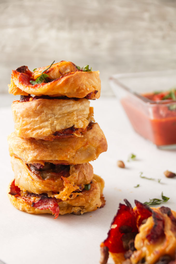 Crispy air fryer pizza rolls in a stack with pizza sauce for dipping.