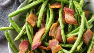 A bowl of green beans with bacon.
