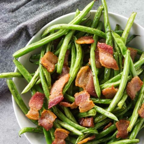 A bowl of green beans with bacon.