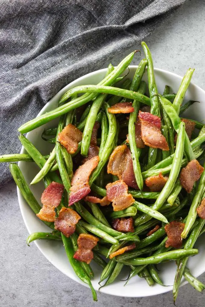 A bowl of green beans with bacon.