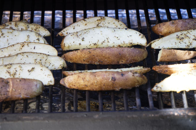 Seasoned potato wedges on a hot grill.