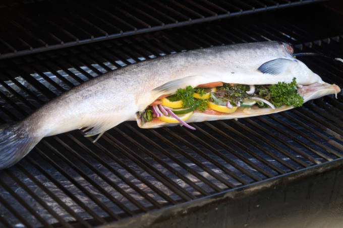 A whole salmon on a hot grill.