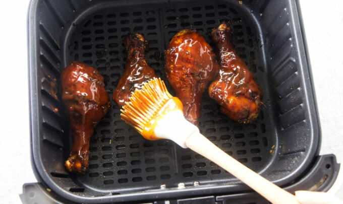 Coating chicken legs with bbq sauce.