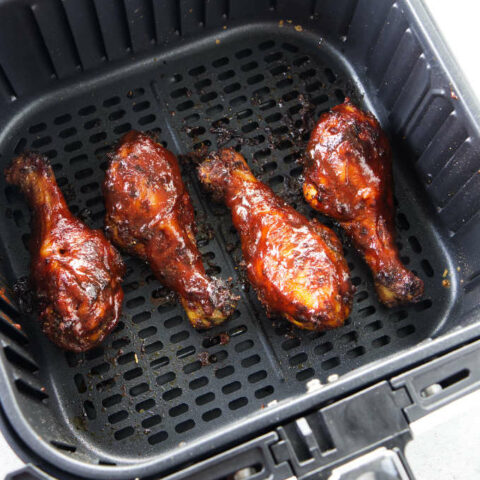 BBQ chicken legs in an air fryer basket.