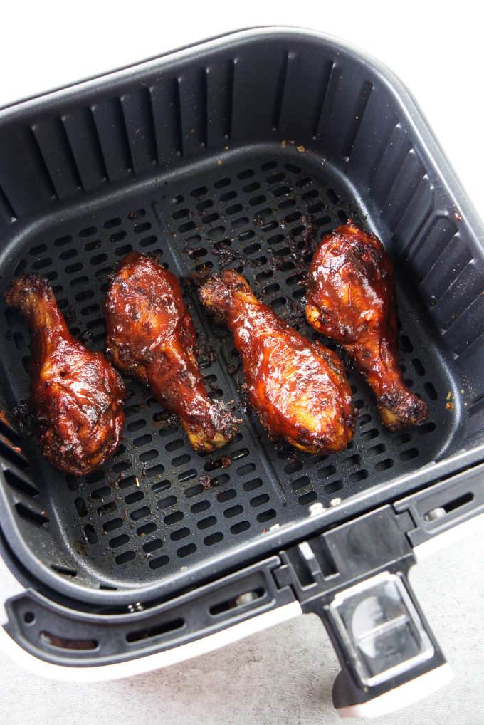 BBQ chicken legs in an air fryer basket.