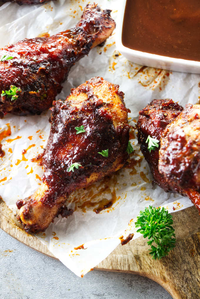 Air fryer drumsticks next to some bbq sauce.