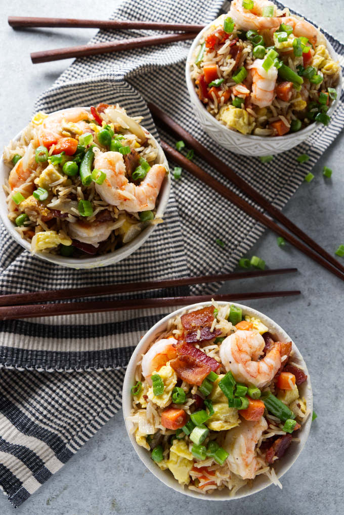 Three bowls of shrimp fried rice cooked on a Blackstone grill.
