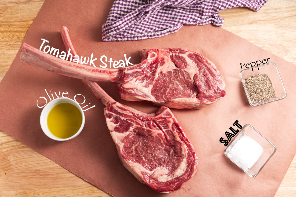ingredients for reverse seared traeger tomahawk steak: olive oil, back pepper, salt, two tomahawk steaks