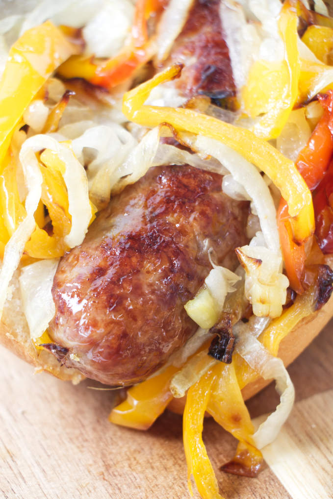 A brat with grilled onions and bell peppers.