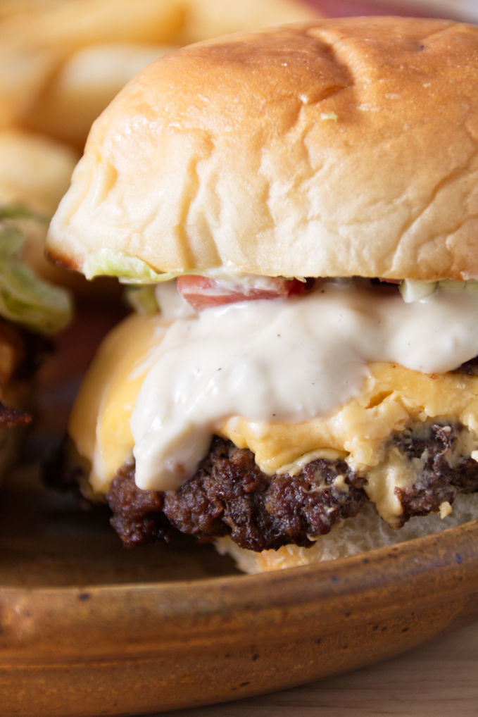 cheesy slider sitting on a ceramic plate with donkey sauce spilling out the side