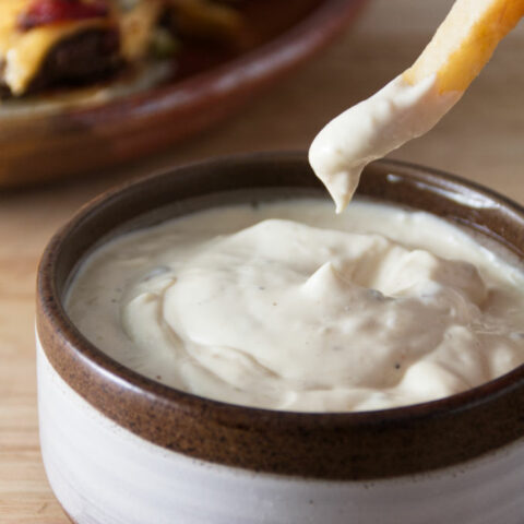 donkey sauce in a ceramic bowl with a french fry dipping in