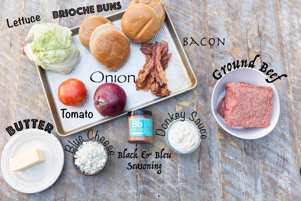 ingredients for blackstone blackened blue cheese stuffed burgers: brioche buns, lettuce, butter, tomato, onion, bacon, black & bleu seasoning, donkey sauce, ground beef